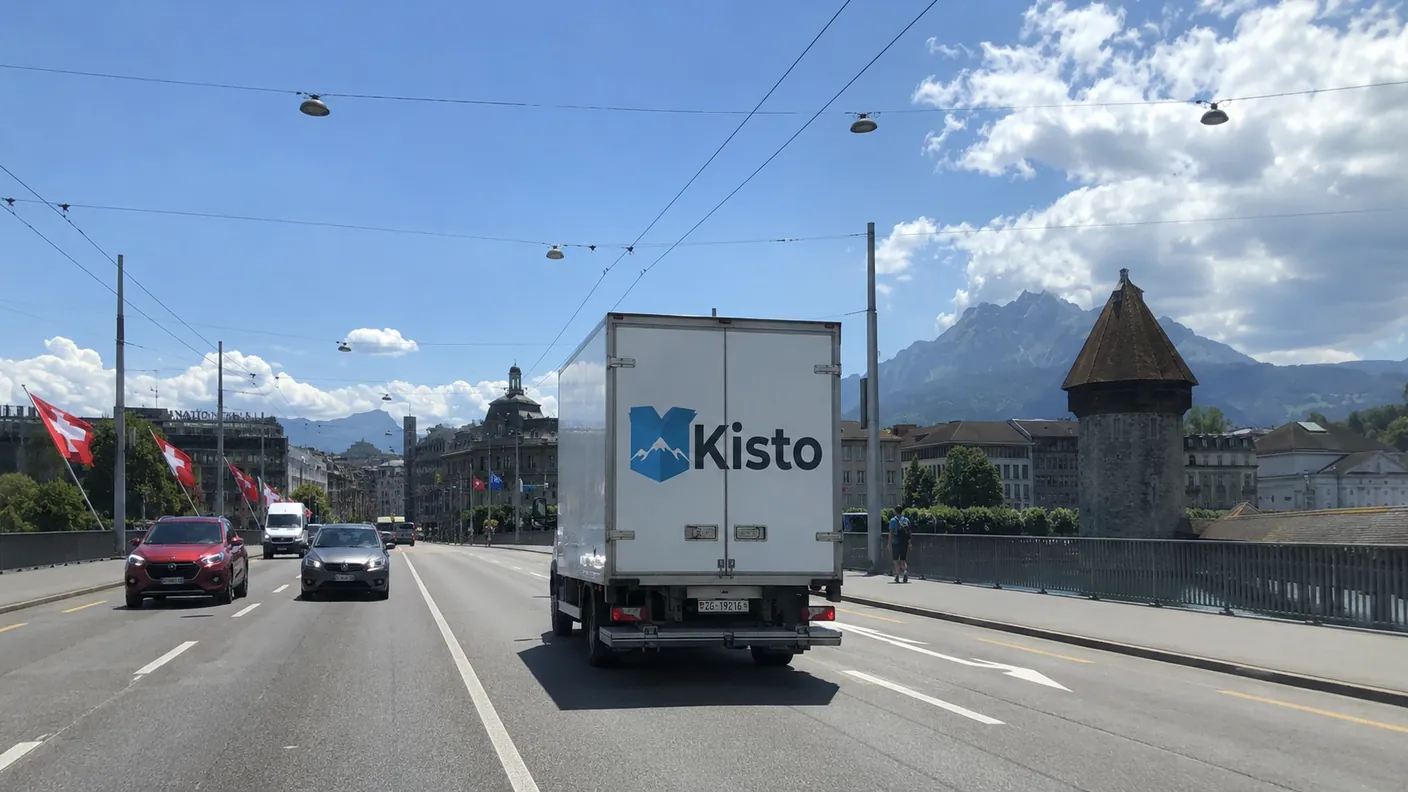 Kisto-Umzugstransporter unterwegs in Luzern vor der Bergkulisse